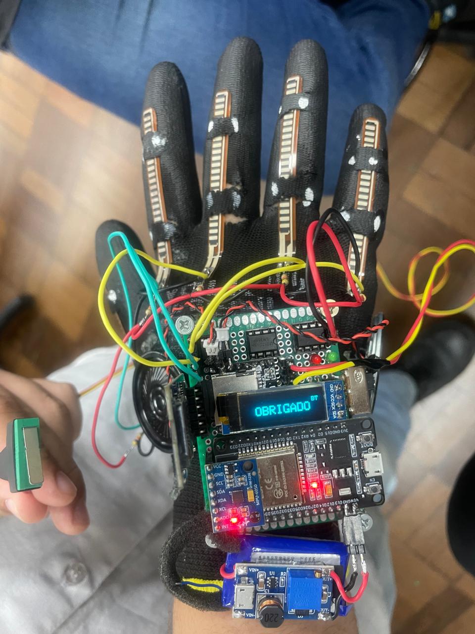 Protótipo físico real da luva SignGloves, com sensores flexíveis, fios, placa eletrônica e pequeno visor